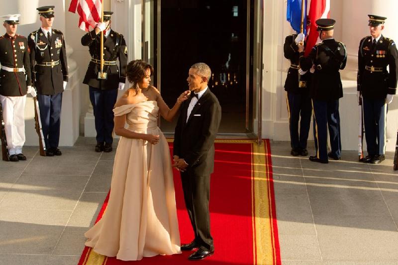 Sau hai nhiệm kỳ, câu chuyện tình yêu đẹp này vẫn thu hút sự quan tâm đặc biệt của báo giới, công chúng bởi những cử chỉ ân cần họ dành cho nhau như cách ông Obama cầm tay che ô cho vợ, hay bà Michelle chỉnh trang cho chồng mình trước ống kính. Ảnh: 