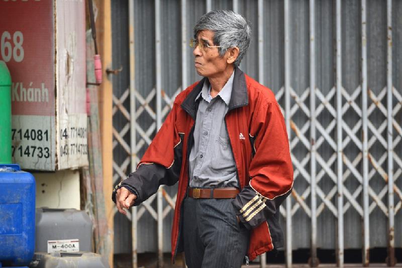 Một người đàn ông thong dong với áo khoác ấm tiến về phía hàng quán bán nước trà nóng.