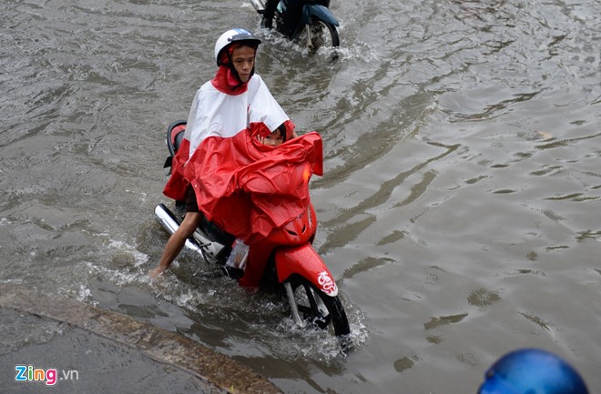 Em bé ngơ ngác ngồi trước xe máy trong cơn ngập trên đường Nguyễn Hữu Cảnh chiều 3/10. 