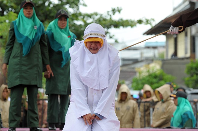 Một phụ nữ Hồi giáo ở Aceh (Indonesia) bị phạt bằng roi sau khi bị bắt gặp thân mật với bạn trai của mình khi chưa cưới. Tỉnh Aceh là nơi áp dụng luật Hồi giáo nghiêm ngặt. Ảnh: AFP.