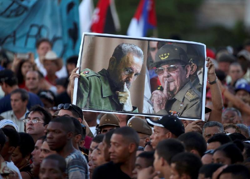 Người dân giơ cao bức ảnh hai nhà lãnh đạo Cuba. Nhiều người tham gia buổi lễ trong trang phục quân nhân.