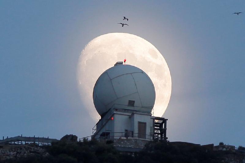 Trăng rằm dần xuất hiện trên nóc một tháp quan sát tại vùng lãnh thổ Gibraltar của Anh. Ảnh: 
