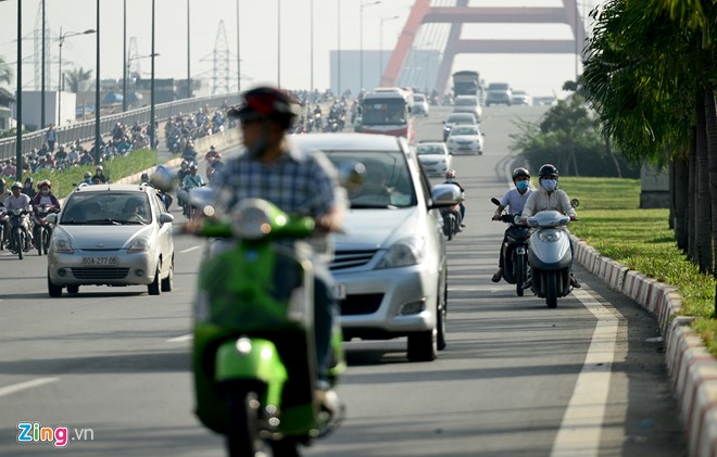Nhiều người lái xe máy chạy sát làn đường trong cùng của ôtô, bên dải phân cách đoạn dốc cầu Bình Lợi.