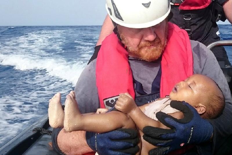 Bức ảnh em bé di cư chết đuối, nằm trong vòng tay nhân viên cứu hộ người Đức hôm 30/5 khiến cộng đồng mạng xót xa. Trước đó, chiếc thuyền chở em bé bất hạnh rời bờ biển gần Sabratha (Libya) vào ngày 26/5 và gặp nạn sau một ngày lênh đênh trên biển. Cơ quan Liên Hợp Quốc về người tị nạn cho biết ít nhất 2.510 người chết trên đường di cư tới châu Âu chỉ trong 5 tháng đầu năm 2016.