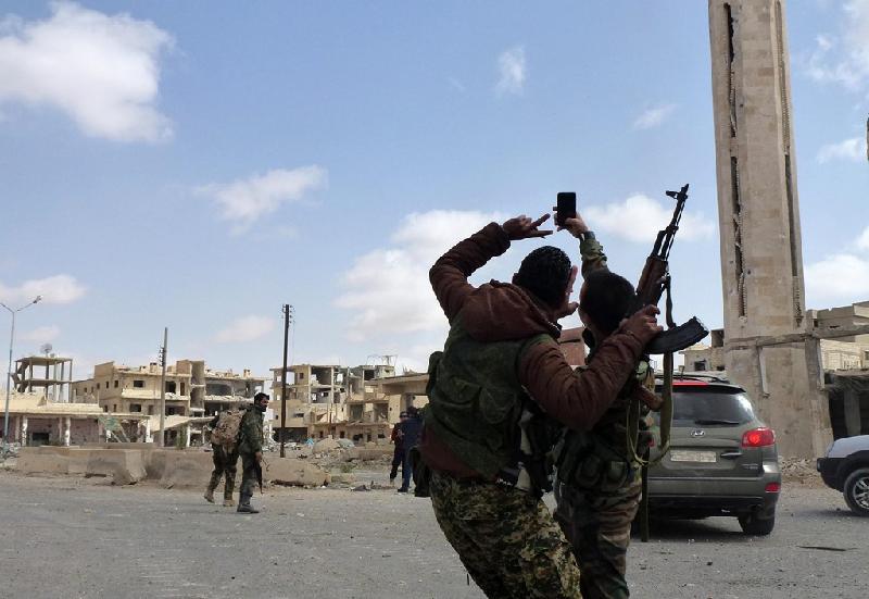 Hai người lính của quân đội Syria giơ điện thoại lên 