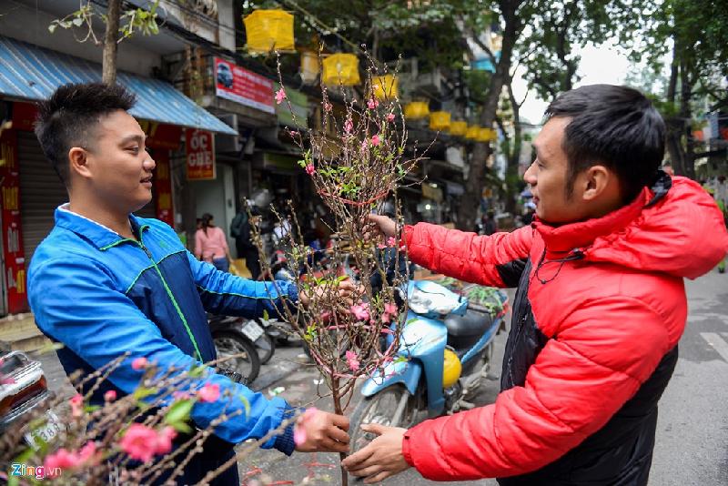 Anh Nguyễn Công Bổng (làng hoa Phú Thượng) giới thiệu cho khách xem đào được mang từ vườn nhà tới, có giá 90.000 đồng mỗi cành.