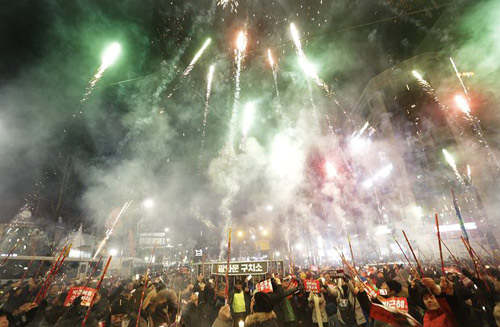Người Hàn Quốc biểu tình dưới ánh sáng rực rỡ của pháo hoa mừng Năm mới. 