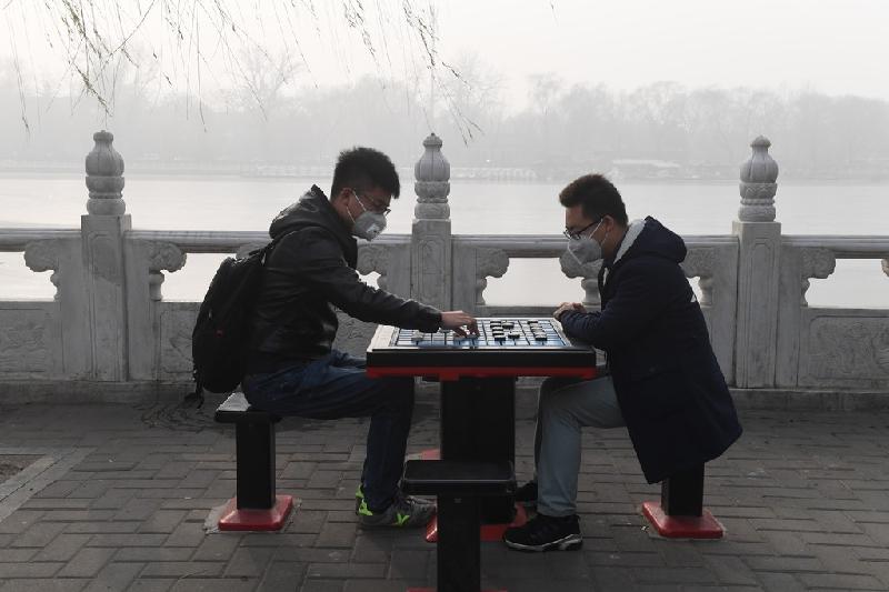Hai chàng trai đánh cờ giữa ngày đầu năm bụi mù dày đặc ở Bắc Kinh. Ảnh: AFP.