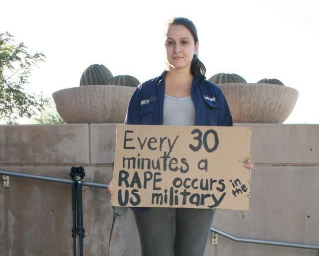 Panayiota Bertzikis, nạn nhân một vụ cưỡng hiếp do nam quân nhân Mỹ thực hiện, giơ tấm biển phản đối nạn tấn công tình dục trong quân đội Mỹ với dòng chữ: 