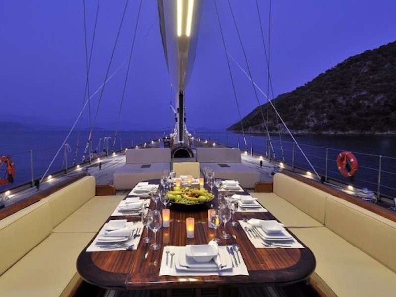 Một bàn ăn đặt trên boong thuyền đủ chỗ cho tất cả hành khách.