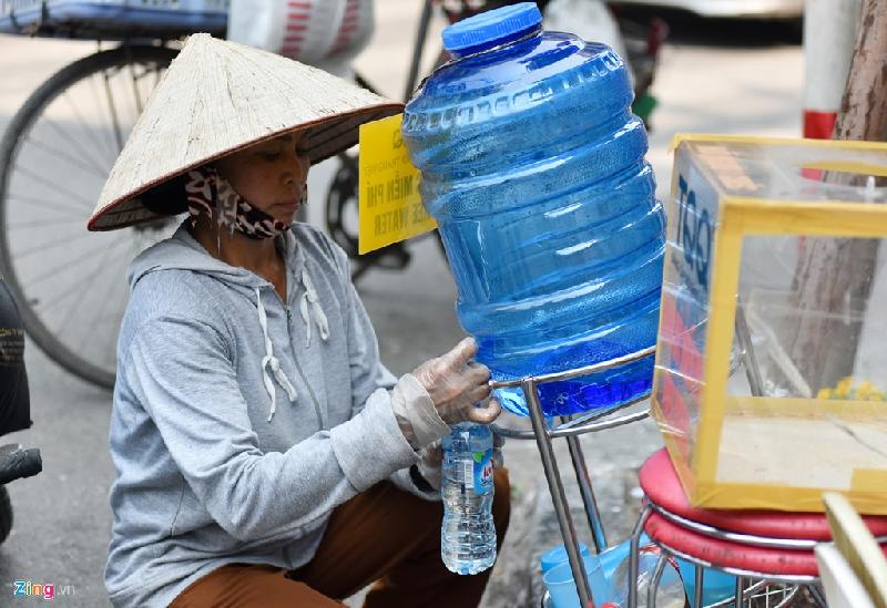 Người lao động tranh thủ dừng lại lấy nước miễn phí trước một cửa hàng trên phố Hàng Ngang.