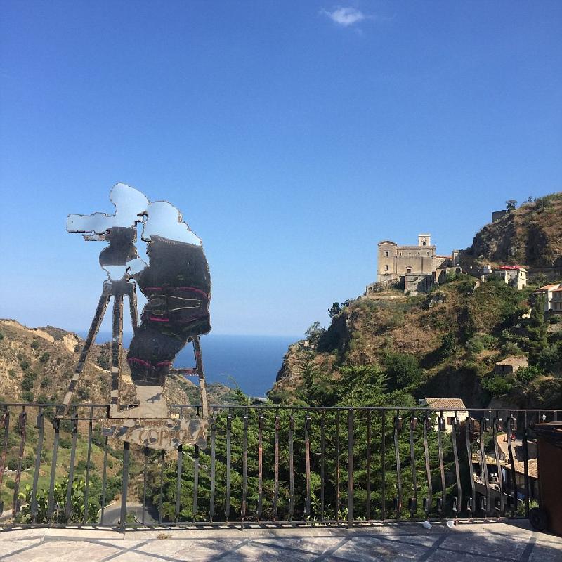 Người dân Sicily ưu ái dành tình cảm cho đạo diễn Francis Ford Coppola bằng một bức tượng kim loại hình ông bên máy quay phim. Phía xa là nhà thờ Santa Maria Degli Angeli, nơi quay cảnh ông trùm Michael Corleone kết hôn với người vợ đầu tiên. Ảnh: 
