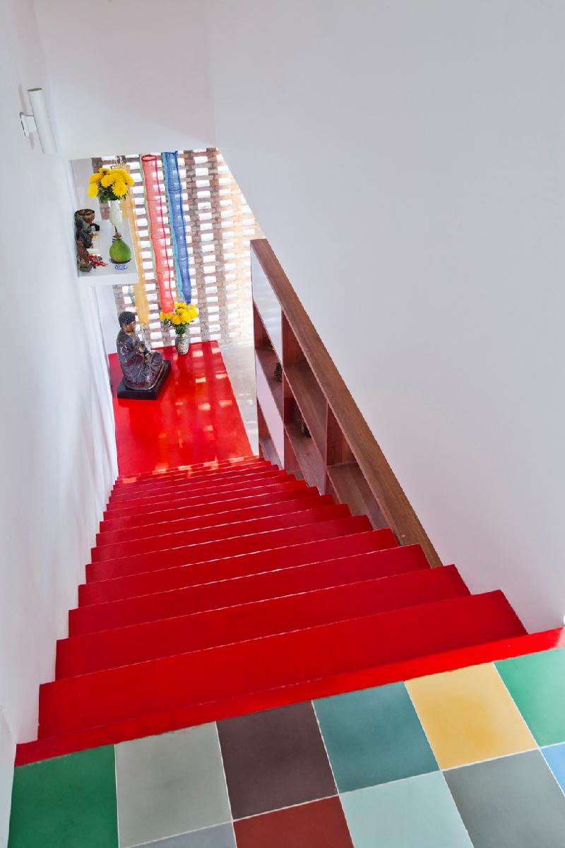 Cầu thang màu đỏ tươi nối từ phòng khách tầng hai lên tầng áp mái.