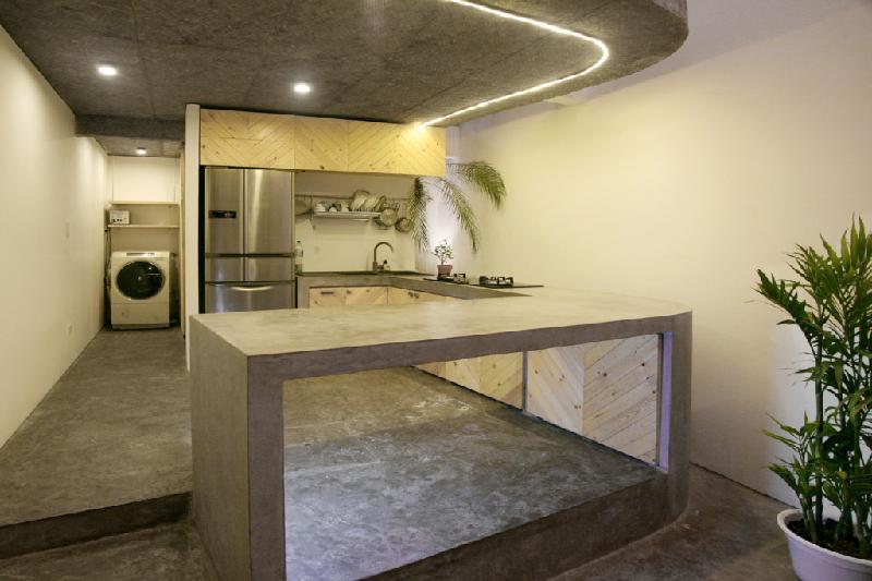 Khu vực bếp tinh tế với thiết kế tối giản, quầy bar và sàn sử dụng chất liệu bê tông mài.