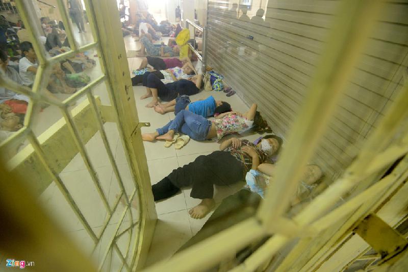 Tại bệnh viện Bạch Mai, người nhà bệnh nhân chen chúc nằm ngủ ở khu vực hành lang khoa khám bệnh trong nóng bức.