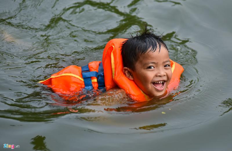 Những em nhỏ chưa biết bơi được bố mẹ sắm cho áo phao để đảm bảo an toàn. Trong ảnh là bé An, 7 tuổi, đang vẫy vùng trong làn nước mát.