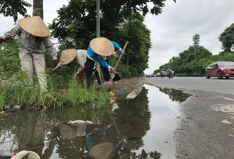 Cách đó khoảng 3 km, qua hầm chui đường tàu (khu vực xã An Khánh), nhóm nữ công nhân khác đang dọn dẹp hai bên vỉa hè đường gom đại lộ Thăng Long.
