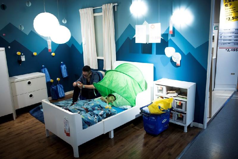 Tiện lợi hơn, nhiều người chọn cửa hàng nội thất làm chỗ để ngủ. Trong ảnh, một ông bố đang trông con ngủ trong cửa hàng nội thất IKEA nổi tiếng hôm 5/7.