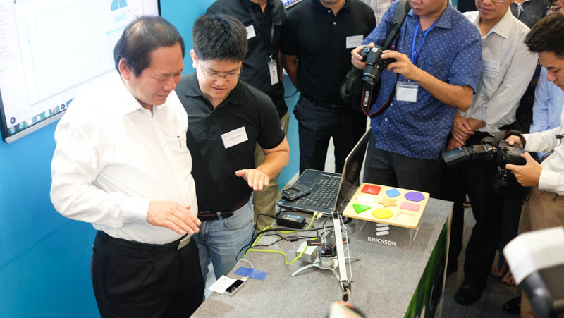 Bộ trưởng Trương Minh Tuấn thử điều khiển cánh tay robot thông qua cảm biến ứng dụng công nghệ kết nối 5G. Ảnh: Mạnh Hưng