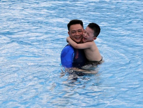 BTV Trần Quang Minh vui đùa cùng con trai dưới hồ bơi. Trái với khuôn mặt tươi cười, vui vẻ của MC 