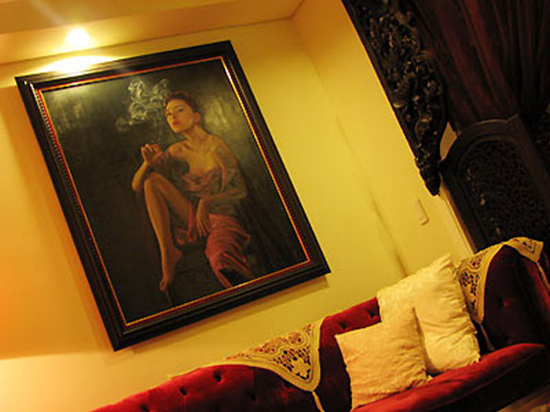 Bức tranh chân dung ấn tượng của nữ chủ nhà treo phía trên bộ ghế sofa màu đỏ.