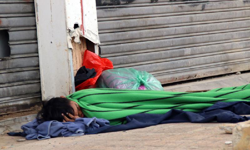 Một người vô gia cư co ro trong tấm mền giữa cái lạnh ở Sài Gòn